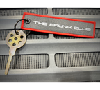 The Frunk Club embroidered key tag with red border and silver lettering, attached to a keychain.