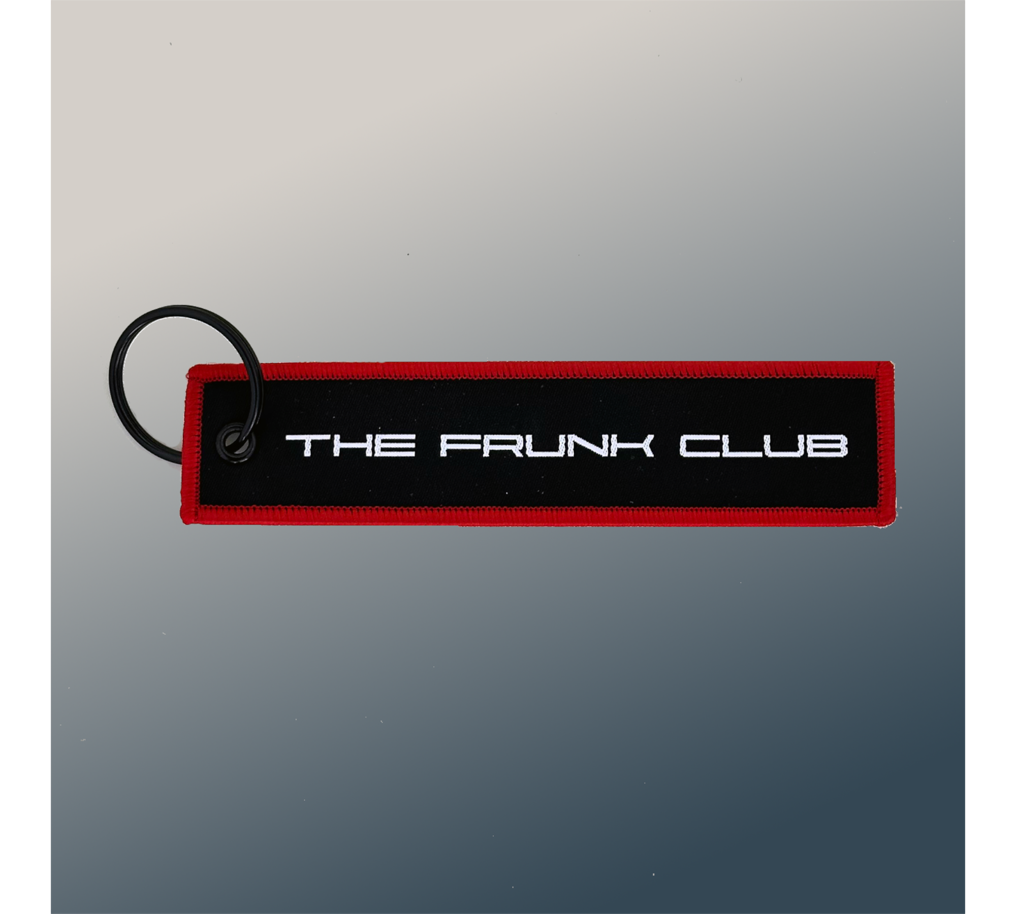 The Frunk Club embroidered key tag with red border and silver lettering, attached to a keyring.
