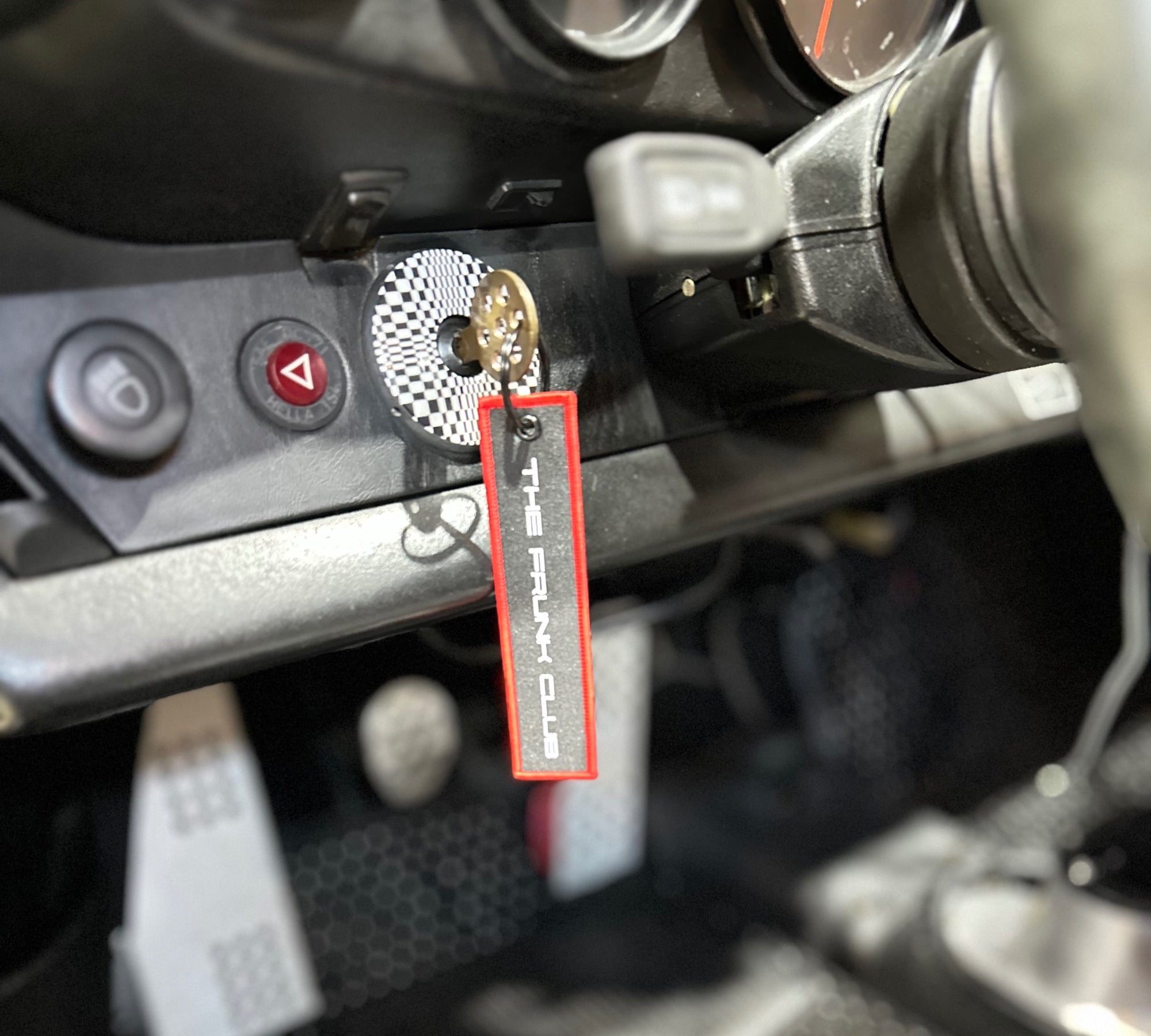The Frunk Club embroidered key tag with red border and silver lettering, attached to car keys.