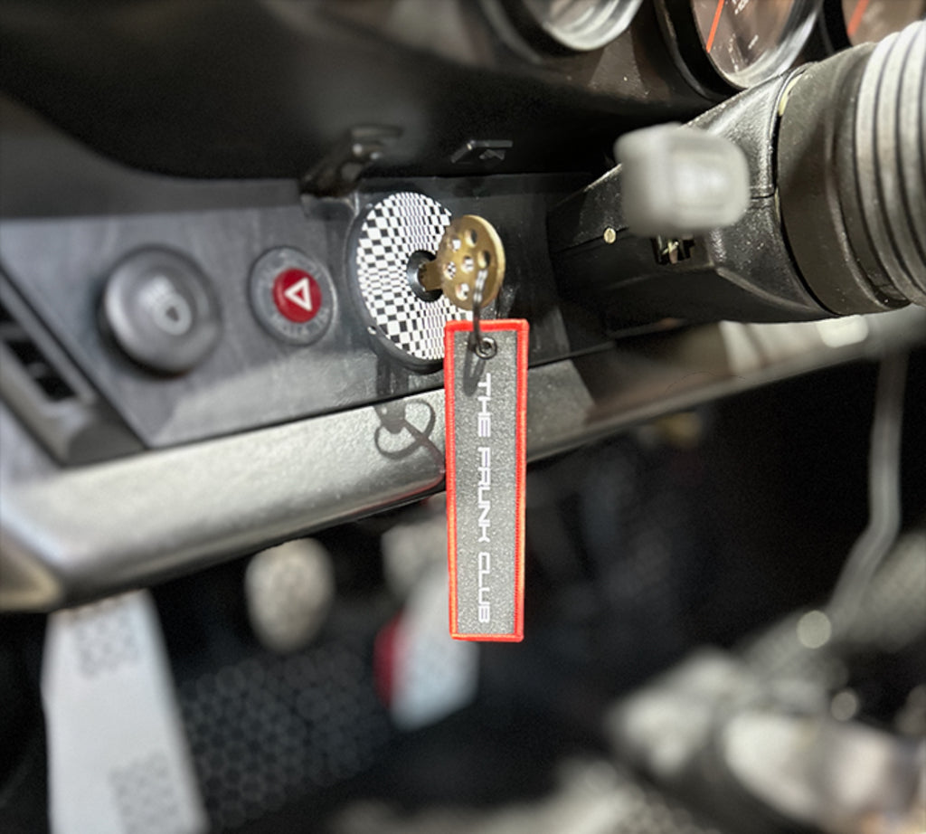 The Frunk Club embroidered key tag with red border and silver lettering, attached to car keys.