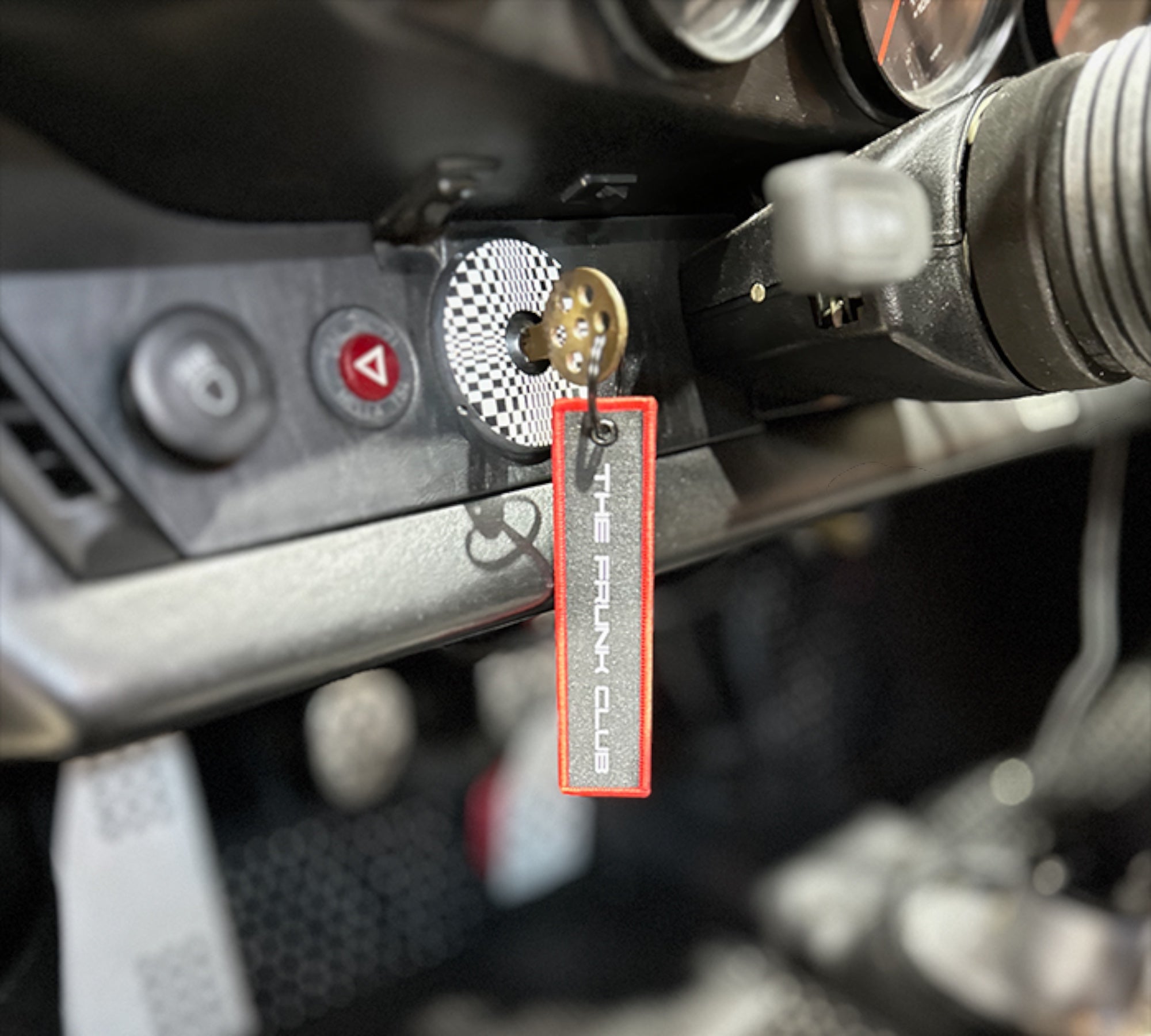 The Frunk Club embroidered key tag with red border and silver lettering, attached to car keys.