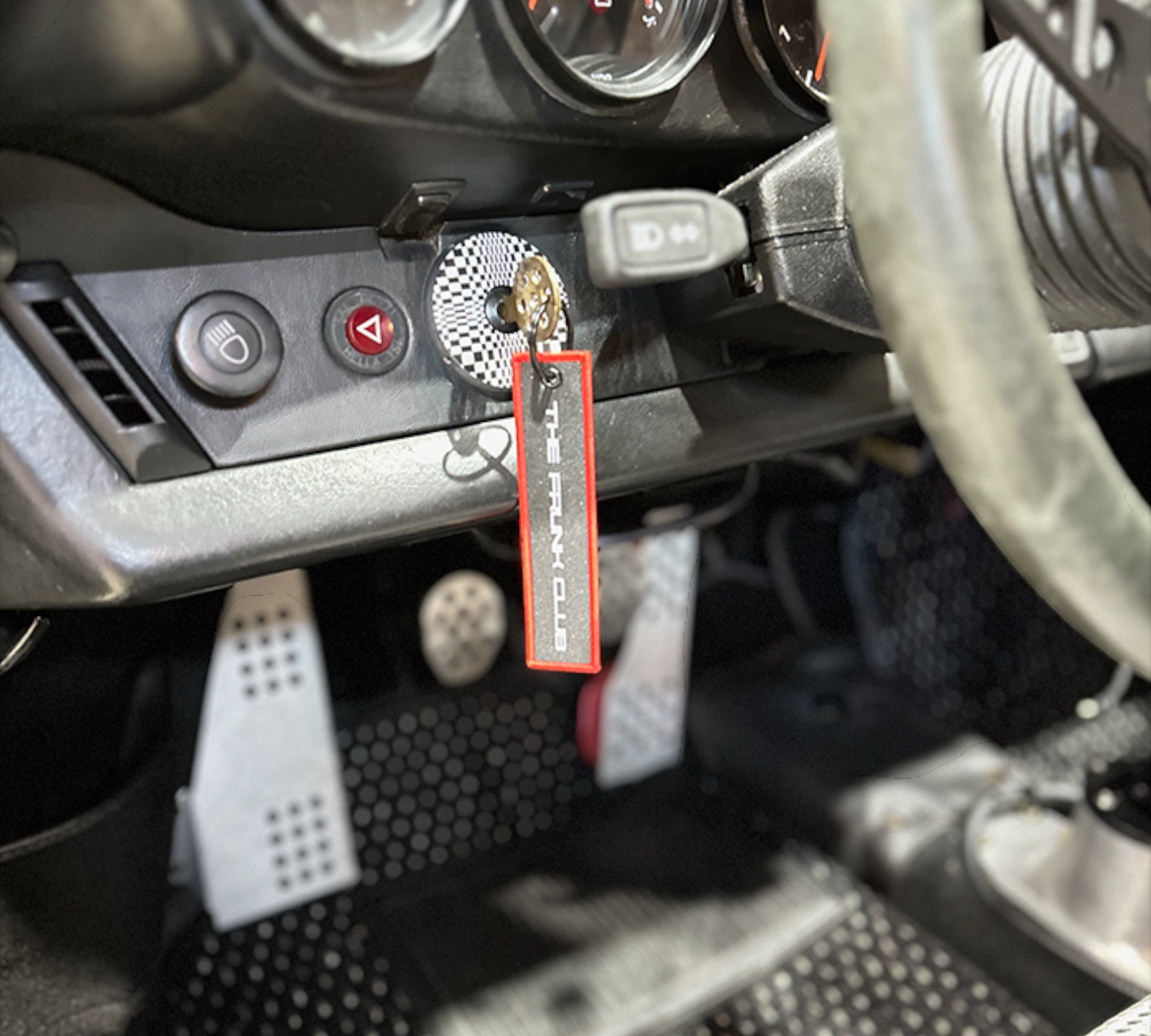 The Frunk Club embroidered key tag with red border and silver lettering, attached to car keys.