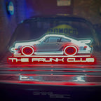 The Frunk Club neon sign featuring a white Porsche 911 silhouette with red wheels and