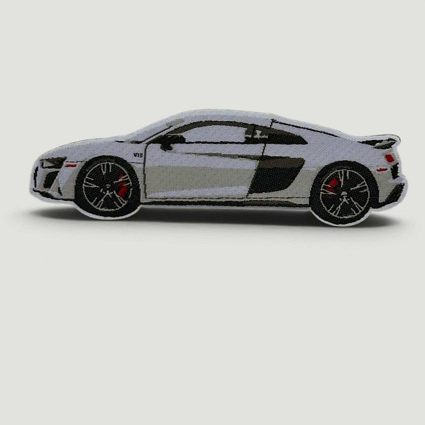 The Frunk Club white Audi R8 embroidered patch with black accents and red brake calipers.