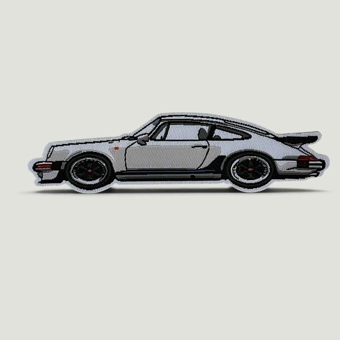 The Frunk Club embroidered patch of a silver Porsche 911 Turbo with black accents and a rear spoiler.