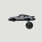 The Frunk Club white woven patch depicting a classic silver Porsche 930 Turbo sports car with black accents and a spoiler.