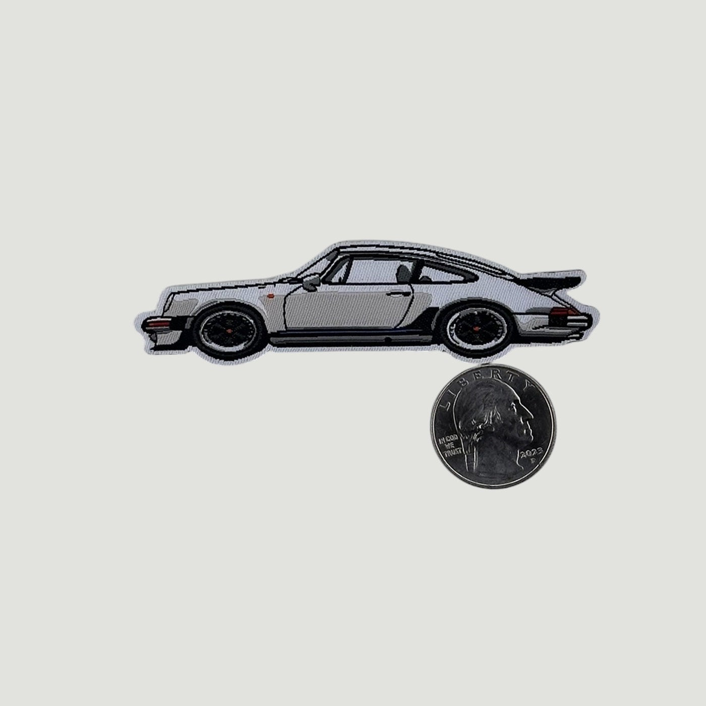 The Frunk Club white woven patch depicting a classic silver Porsche 930 Turbo sports car with black accents and a spoiler.